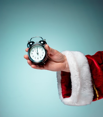 Santa holding an old alarm clock on blue background