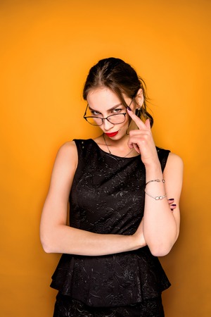 The young woman's portrait with wary emotions on orange studio backgroundの写真素材