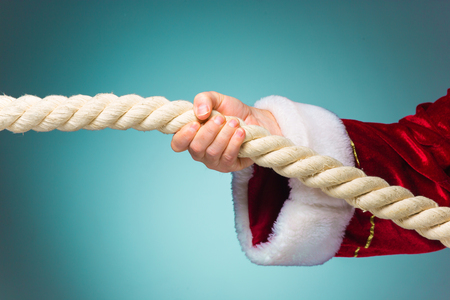 The hand of santa claus pulling the rope on blue backgroundの写真素材