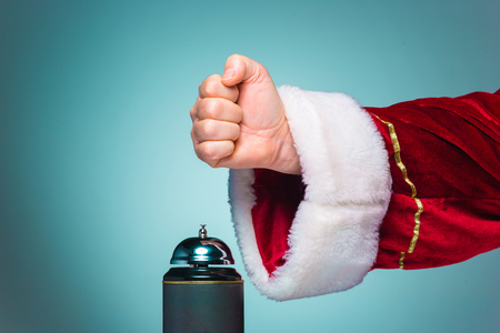 The hand of santa claus pressing on the bell on blue backgroundの写真素材