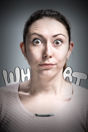 Portrait of young woman with shocked facial expression  over gray backgroundの写真素材