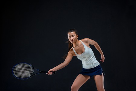 Portrait of beautiful girl tennis player with a racket on dark backgroundの写真素材