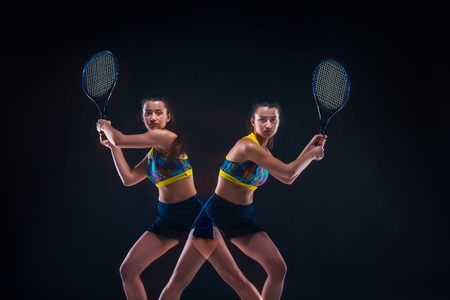 Portrait of beautiful girl tennis player with a racket on dark background
