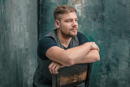 Portrait of serious man sitting on the chair in studioの写真素材