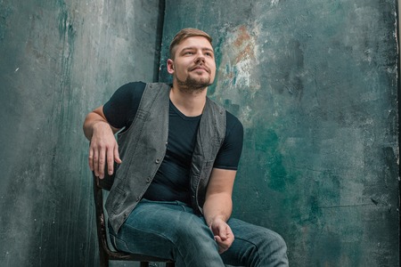 Portrait of smiling happy man sitting on the chair in studio