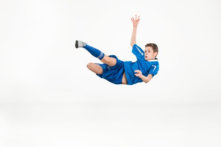 Young boy with soccer ball doing flying kickの写真素材