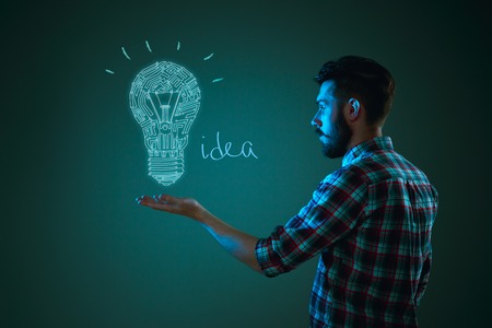 Handsome young man with idea bulb on blue