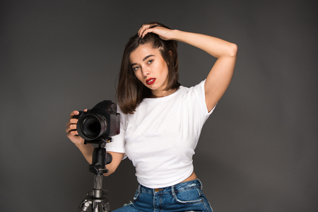 Portrait of a young woman with camera on the gray backgroundの写真素材