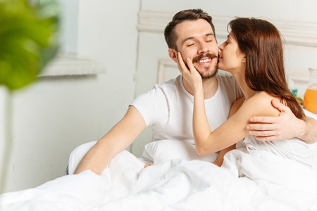 Young adult heterosexual couple lying on bed in bedroomの写真素材