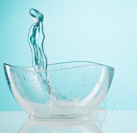 The water splashing to glass bowl on white backgroundの写真素材