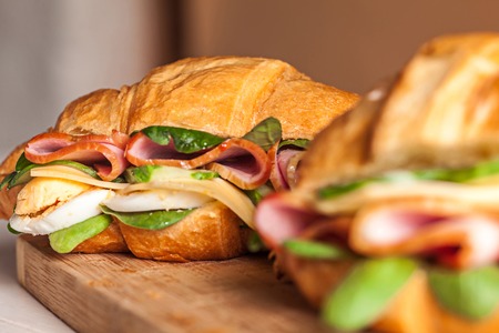 Croissants sandwiches on the wooden cutting boardの写真素材