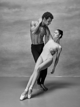 Couple of ballet dancers posing over gray backgroundの写真素材