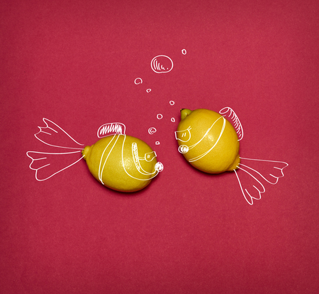 The pop art collage of fresh lemons and drawing fishes on red backgroundの写真素材