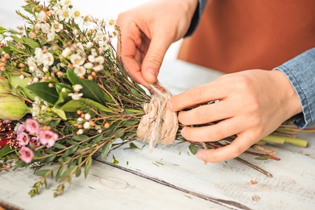 Florist at work: the female hands of woman making fashion modern bouquet of different flowersの写真素材