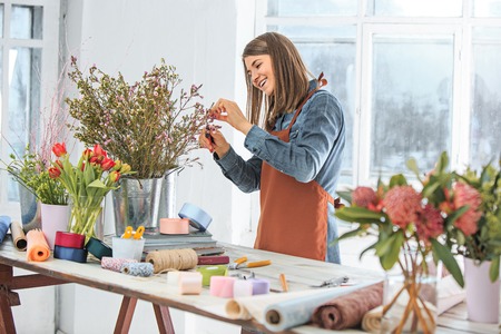 Florist at work: the young girl making fashion modern bouquet of different flowersの写真素材