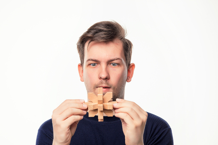 Attractive 25 year old business man looking confused at wooden puzzle.の写真素材