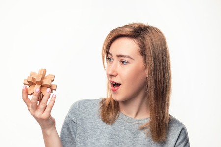 Attractive 24 year old business woman looking confused with wooden puzzle.