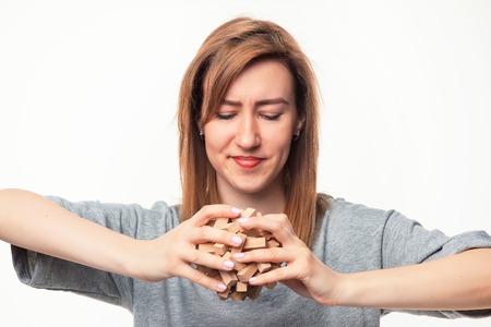 Attractive 24 year old business woman looking confused with wooden puzzle.の写真素材