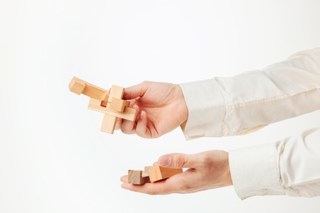 The toy wooden puzzle in hands solated on white backgroundの写真素材