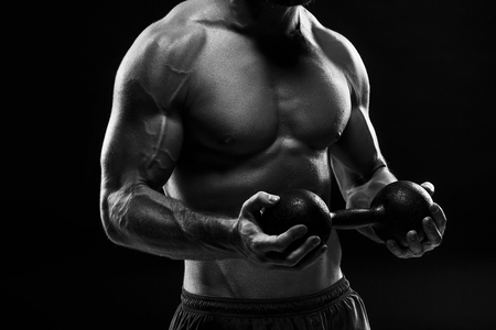 The torso of attractive male body builder on black background.の写真素材