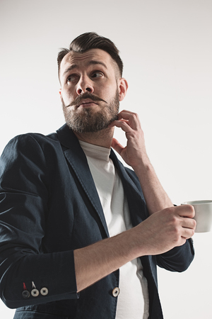 Portrait of stylish handsome young man with cup of coffeeの写真素材