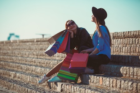 Two girls walking with shopping on city streetsの写真素材