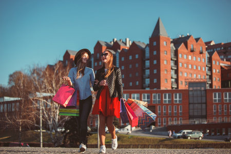 Two girls walking with shopping on city streetsの写真素材