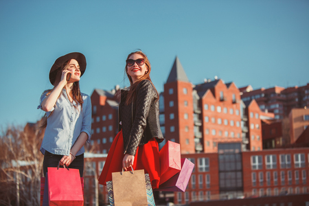 Two girls walking with shopping on city streetsの写真素材