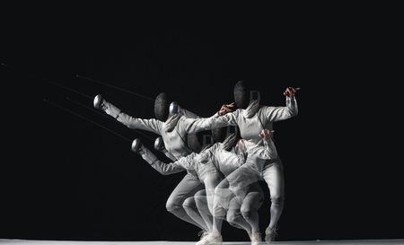 Full-length portrait of woman wearing white fencing costume on black