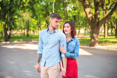 Happy young couple at park standing and laughing on the bright sunny dayの写真素材