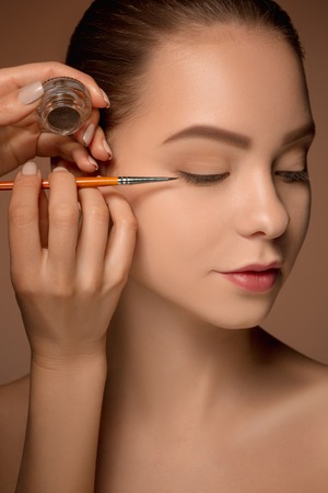 Beautiful female eyes with make-up and brushの写真素材
