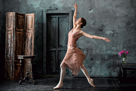Young and incredibly beautiful ballerina is posing and dancing in a black studioの写真素材