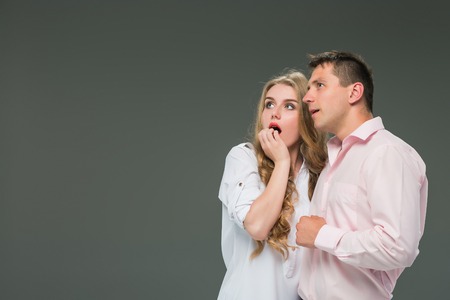 Portrait of a young couple standing against gray background