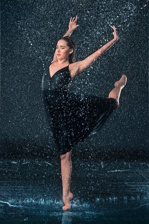 The young beautiful modern dancer dancing under water drops