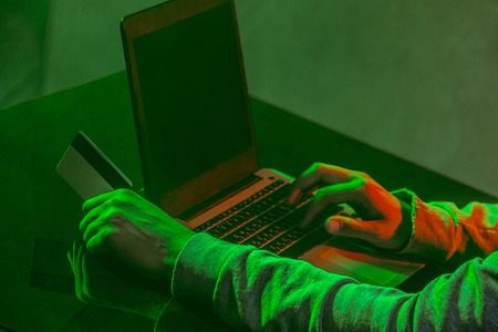 Hooded computer hacker stealing information with laptopの写真素材