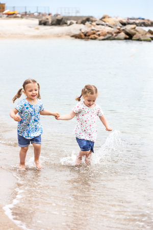 Children on the sea beach. Twins going along sea water.の写真素材