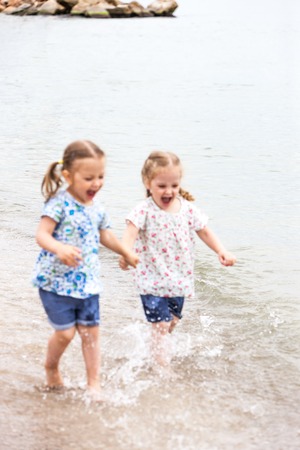 Children on the sea beach. Twins going along sea water.の写真素材