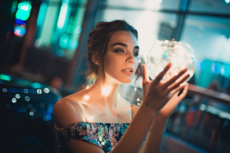 Beautiful young woman smiling and talking garlands of lights at city