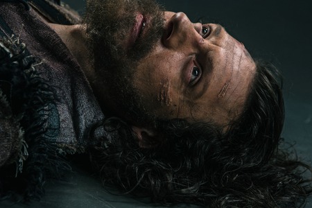 Halloween zombie lying on paving asphalt. Vampire hipster with red blood outdoors. Holiday celebration concept. Man with bloody beard and hair.の写真素材