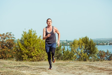 Running sport. Man runner sprinting outdoor in scenic nature. Fit muscular male athlete training...