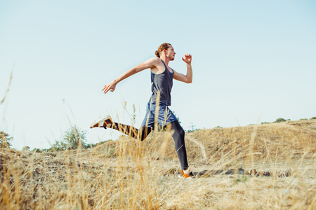Running sport. Man runner sprinting outdoor in scenic nature. Fit muscular male athlete training trail running for marathon run.の写真素材