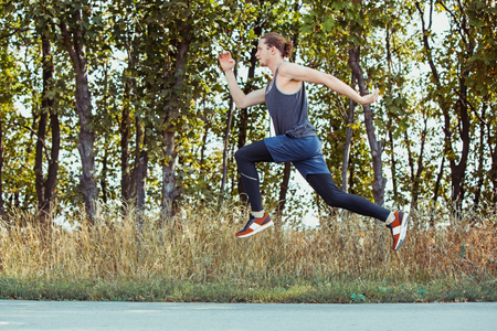 Running sport. Man runner sprinting outdoor in scenic nature. Fit muscular male athlete training...