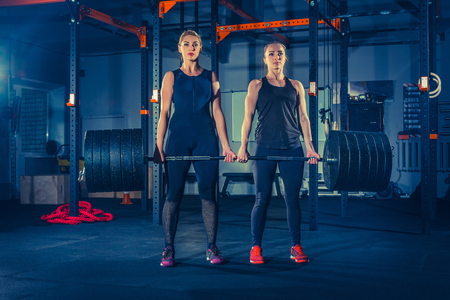 Fit young women lifting barbells and working out in a gymの写真素材