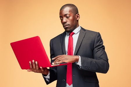 Handsome Afro American man sitting and using a laptopの写真素材