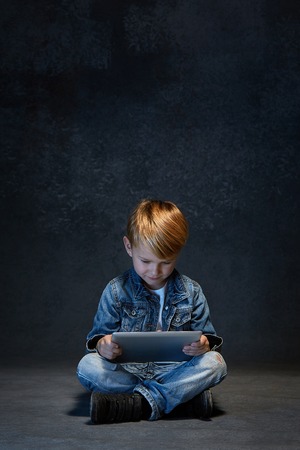 Little boy sitting with tablet in studioの写真素材
