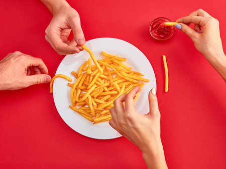 Young woman eating french fries potato with ketchup in a restaurantの写真素材