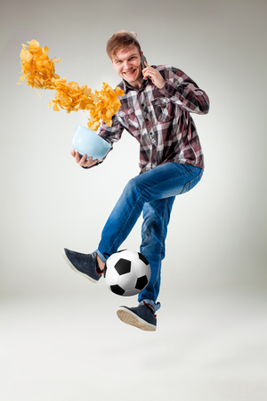 Portrait of young man with smart phone and football ballの写真素材