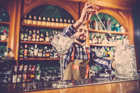 Barman making an alcoholic cocktail at the bar counter on the bar backgroundの写真素材
