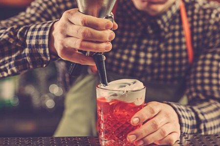 Barman making an alcoholic cocktail at the bar counter on the bar backgroundの写真素材