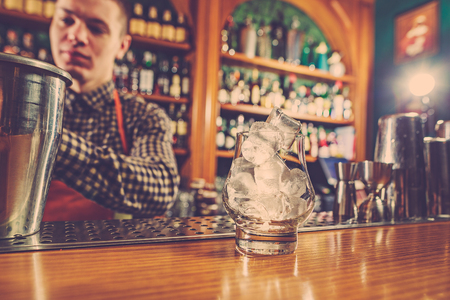 Barman making an alcoholic cocktail at the bar counter on the bar backgroundの写真素材